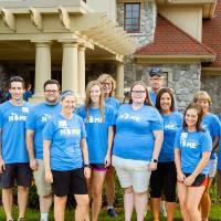 Alumni pose in front of the Alumni House
